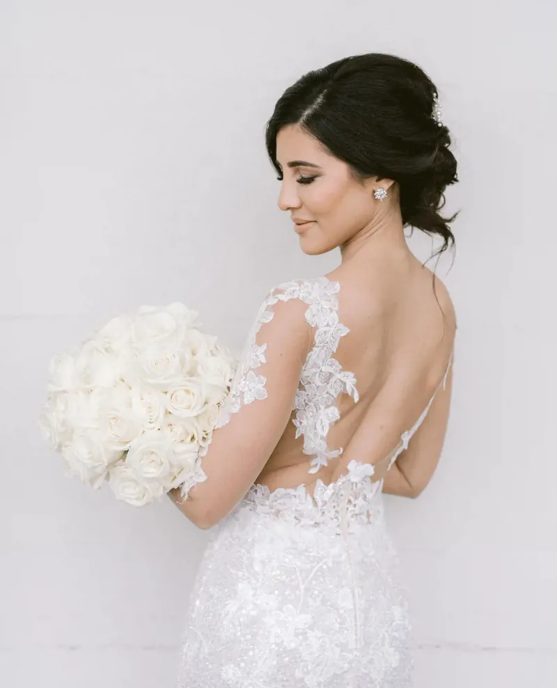 A smiling bride holding white roses